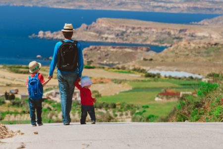 father with two kids walking on scenic road, travel concept